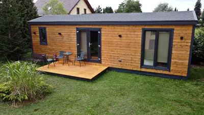 a tiny house with a deck and a table and chairs at Penzion Na Americe in Nové Jirny