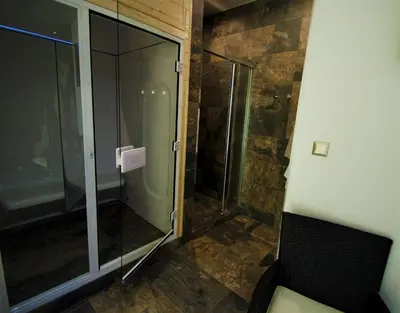a glass shower in a room with a bench at Penzion Na Americe in Nové Jirny