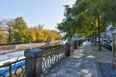 a sidewalk next to a river with trees and a fence at Panoramic Loft in Prague