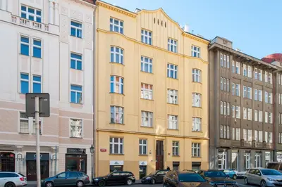a yellow building with cars parked in front of it at Spacious And Bright Apartment Dusni 13 in Prague