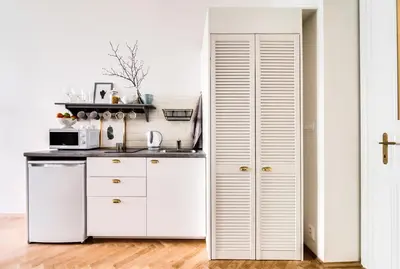 a kitchen with white cabinets and a white door at Trendy Local Apartment in Prague
