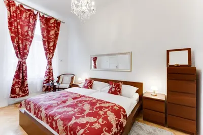 a bedroom with a bed with red curtains and a chandelier at Old Town Square Royal Apartment in Prague
