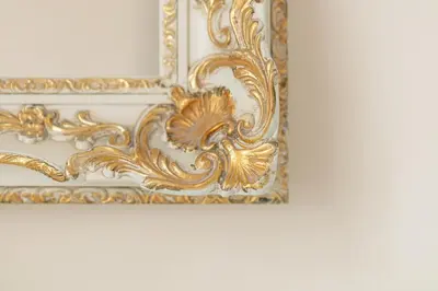 an ornate gold picture frame on a white wall at Alqush Downtown Hotel in Prague