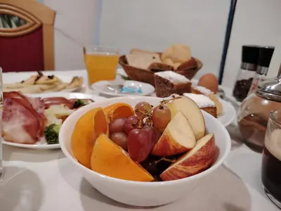 a bowl of fruit on a table with plates of food at Hotel Legie in Prague