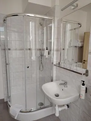 a white bathroom with a shower and a sink at Hotel Legie in Prague