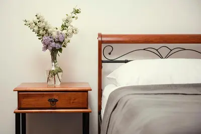 a vase of flowers on a night stand next to a bed at Ostende Chocerady - ubytování u řeky in Chocerady