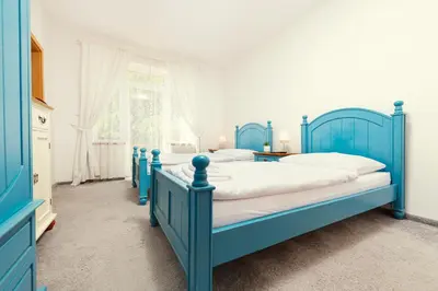 a blue bedroom with two beds and a window at Ostende Chocerady - ubytování u řeky in Chocerady