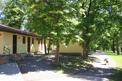a child walking in front of a building with trees at Resort Beach Nová Živohošť in Křečovice