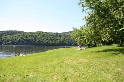 a group of people laying on the grass near a lake at Resort Beach Nová Živohošť in Křečovice