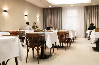 a restaurant with white tables and people sitting at them at Hotel Prokop Square in Prague