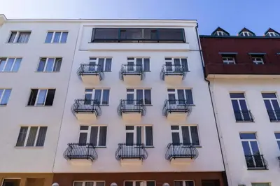 a tall white building with balconies on it at Penzion Homer Poděbrady in Poděbrady