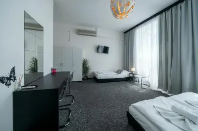 a hotel room with a bedroom with two beds and a desk at Penzion Homer Poděbrady in Poděbrady