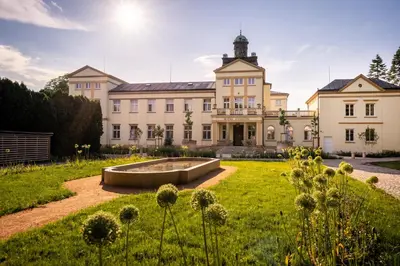 a large building with a garden in front of it at Hotel Zámeček in Poděbrady