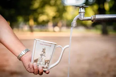 a person is holding a cup under a water faucet at Hotel Zámeček in Poděbrady