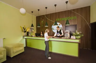 a woman standing in front of a reception counter at Hotel Zámeček in Poděbrady