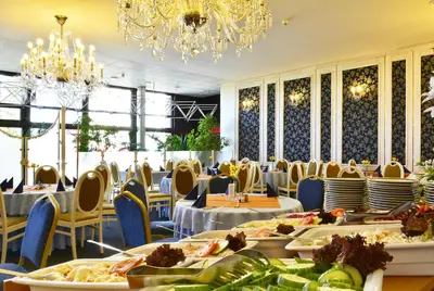 a dining room with tables and chairs and a chandelier at Hotel Olympik in Prague