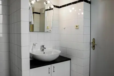 a white bathroom with a sink and a mirror at Vila Josefina in Prague