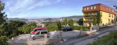 two cars parked in front of a yellow house at Pension PRIMUS in Beroun