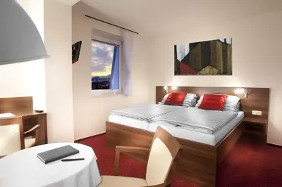 a bedroom with a bed and a table and a desk at Pension PRIMUS in Beroun