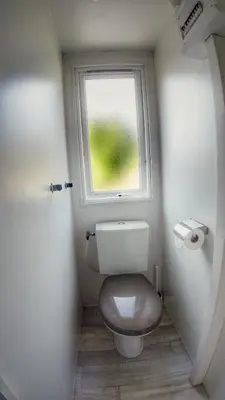 a small bathroom with a toilet with a window at Camping Sokol Praha in Prague