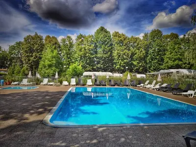 a large swimming pool with chairs and umbrellas at Camping Sokol Praha in Prague