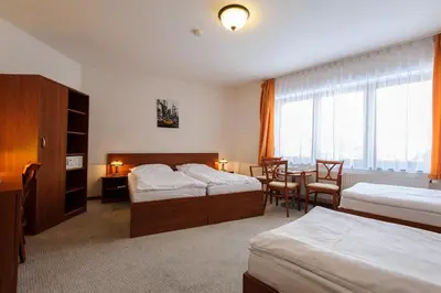a hotel room with two beds and a table and chairs at Alexis in Prague