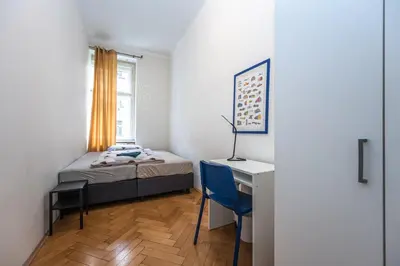 a bedroom with a bed and a desk and a window at Vltava Apartments Prague 7 in Prague