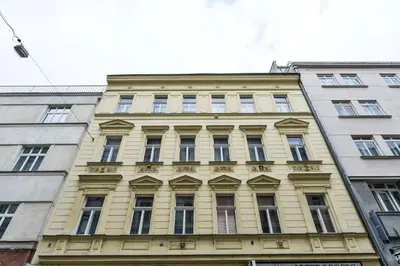 a yellow building with many windows in front of two buildings at Vogue apartment near by Wenceslas Square in Prague