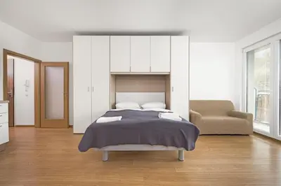 a white bedroom with a bed and a chair at Prague City Residence in Prague