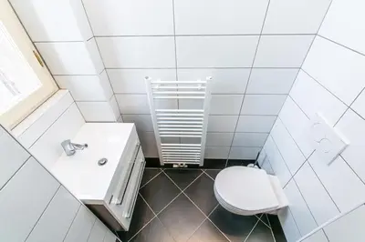 a white bathroom with a toilet and a sink at Letná Apartments in Prague