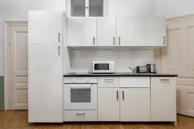 a white kitchen with white cabinets and a microwave at Letná Apartments in Prague