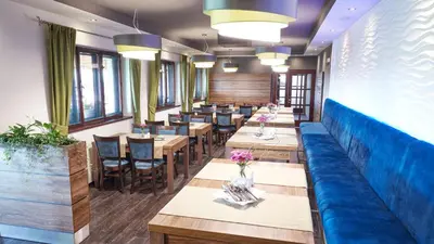 a restaurant with wooden tables and blue benches at Penzion Archery in Nová Ves