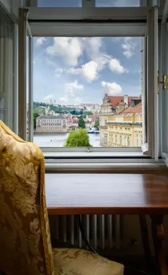 a window with a view of a river and buildings at Charles Bridge Palace in Prague