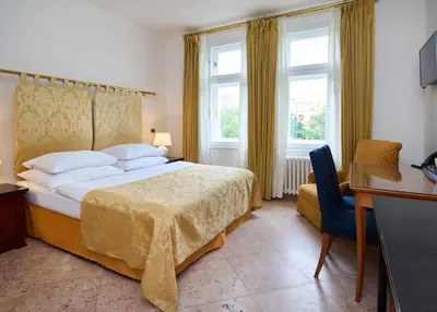 a hotel room with a bed and a desk and window at La Fenice in Prague
