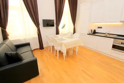 a living room with a white table and a kitchen at Luxury apartments Krocínova in Prague