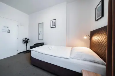 a bedroom with a large bed with white sheets at Penzion Homér Slaný in Slaný