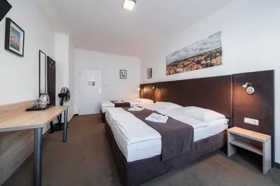 a hotel room with two beds and a desk at Penzion Homér Slaný in Slaný