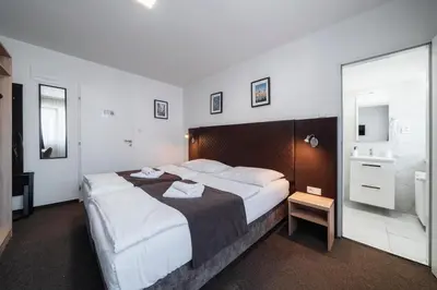 a bedroom with a large bed and a bathroom at Penzion Homér Slaný in Slaný