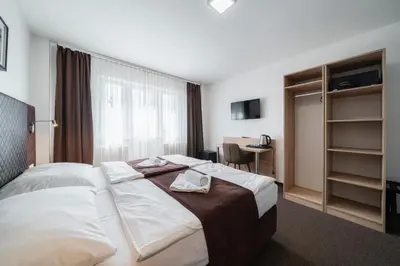 a hotel room with a bed with towels on it at Penzion Homér Slaný in Slaný