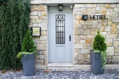 a stone house with a white door and two potted trees at Art Deco Hotel Hoffmann in Kladno