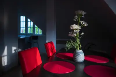 a dining room table with red chairs and a vase with flowers at Art Deco Hotel Hoffmann in Kladno
