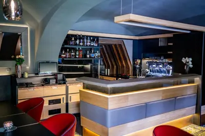 a bar in a restaurant with red chairs at Maxmilian Lifestyle Resort in Loučeň