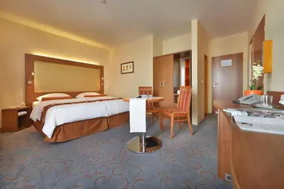 a hotel room with a large bed and a kitchen at Maxmilian Lifestyle Resort in Loučeň