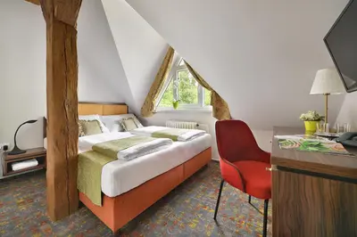 a bedroom with a large bed and a red chair at Maxmilian Lifestyle Resort in Loučeň