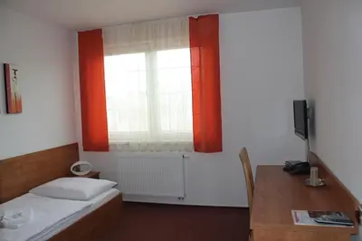 a bedroom with a bed and a window and a desk at Hotel Olympionik in Mělník