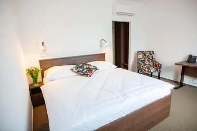 a small bedroom with a bed and a chair at Hotel Olympionik in Mělník