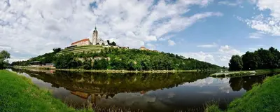 a building on top of a hill next to a river at Hotel Swami in Mělník