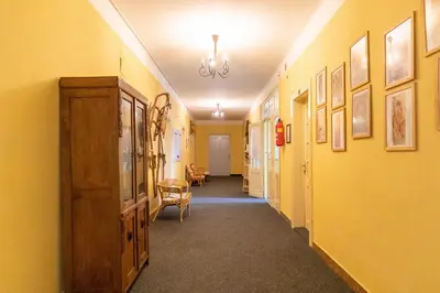 a hallway with yellow walls and a hallway with a chair at Hostel Dakura in Prague