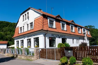 a white building with a wooden fence in front of it at Hotel U Berounky in Srbsko