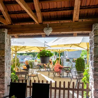 a group of people sitting at a patio with umbrellas at Hotel U Berounky in Srbsko